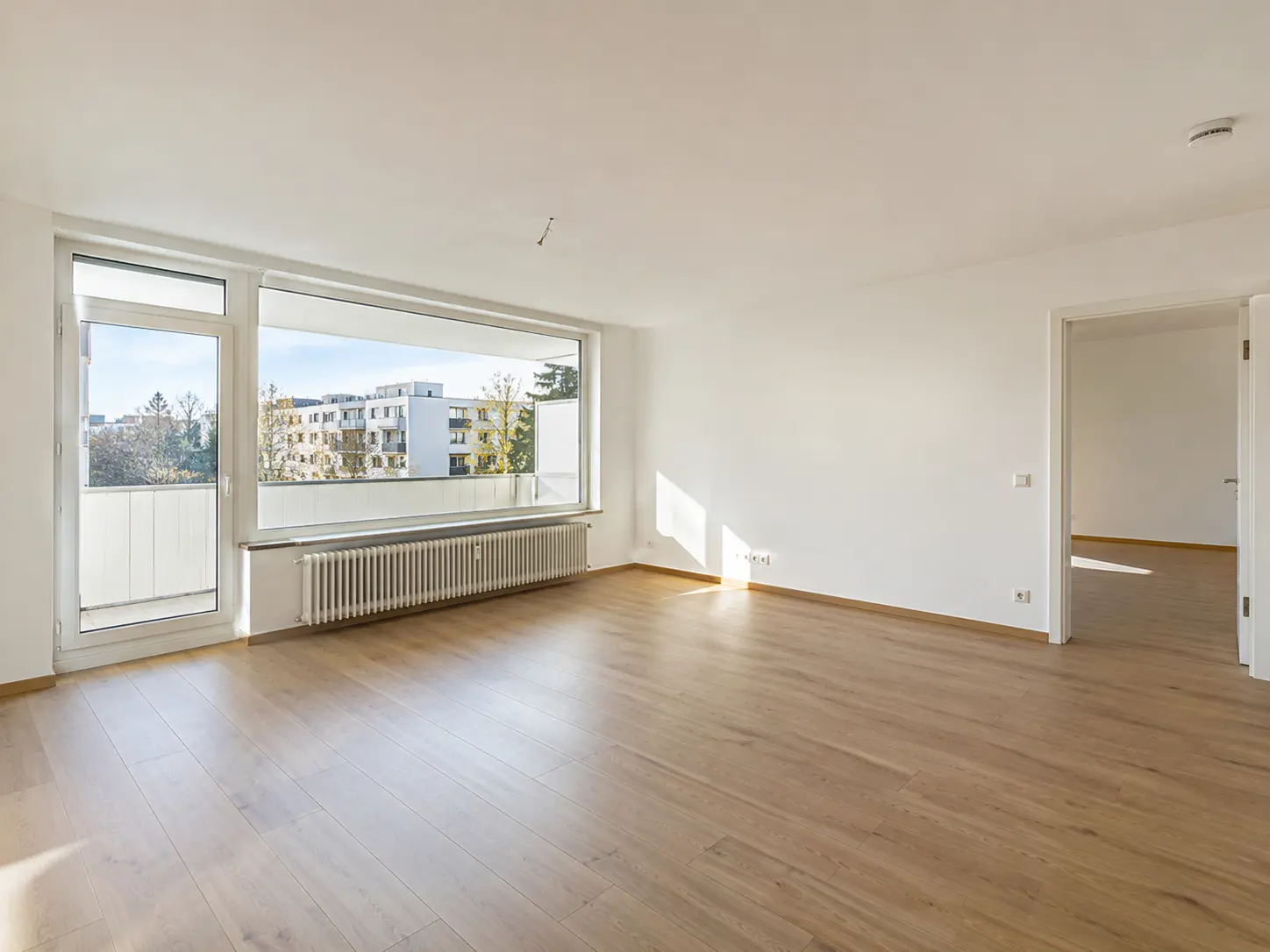 Wohnraum mit Panoramafenster, Balkontür und Laminatboden in einer Mietwohnung in Frankfurt am Main